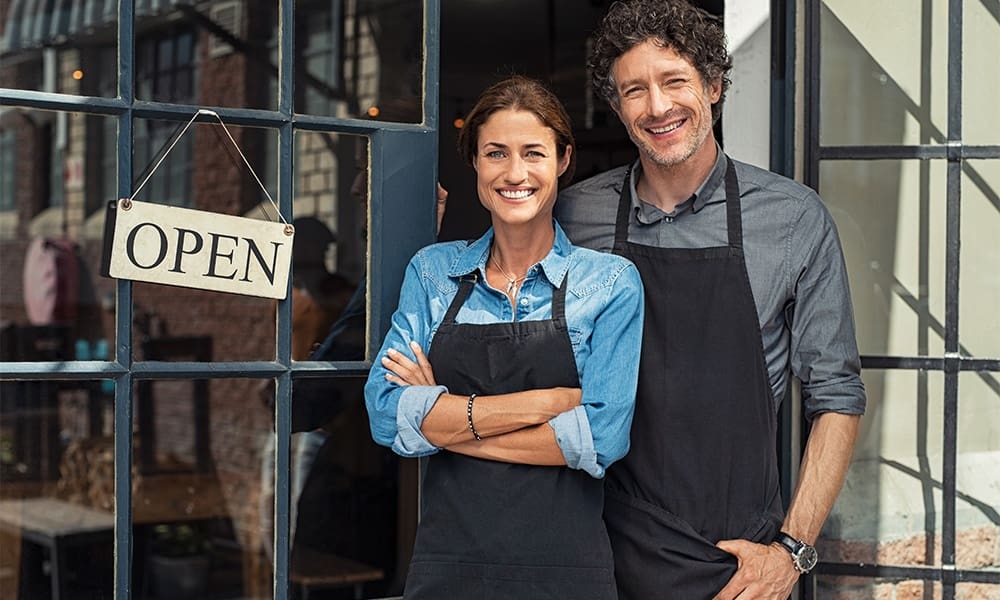 Insurance for Small Businesses - What You Need to Know -Small Business Owners Couple Standing Outside of Their New Shop